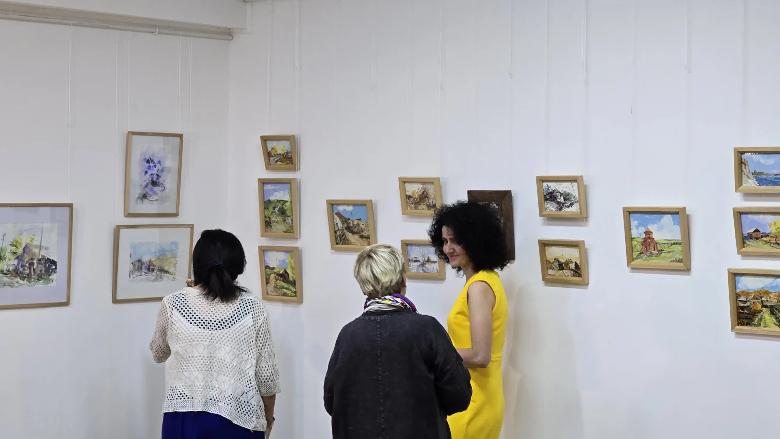 Guests looking at a row of small framed watercolour works