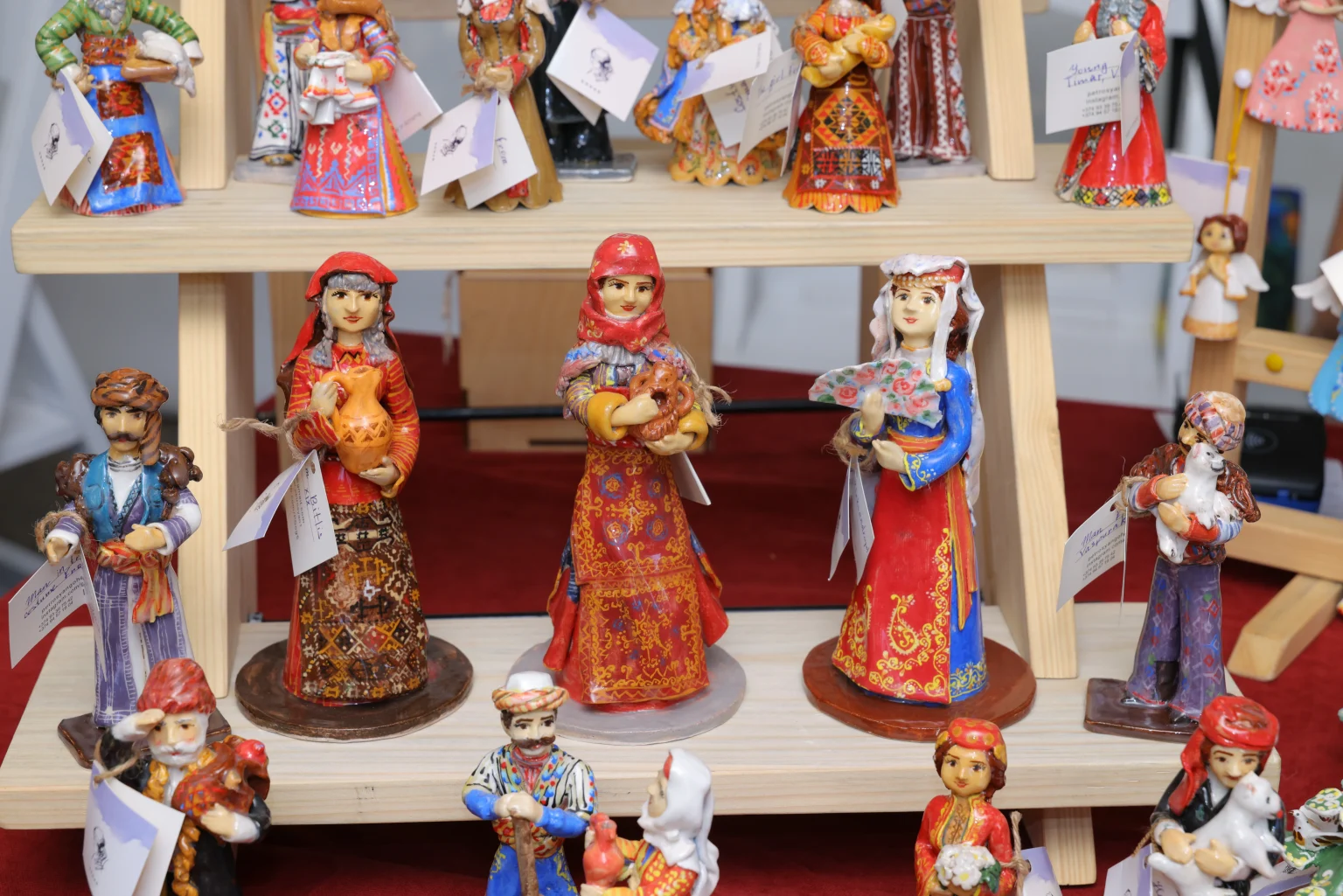 Clay figurines in Armenian national costume standing on wooden shelves